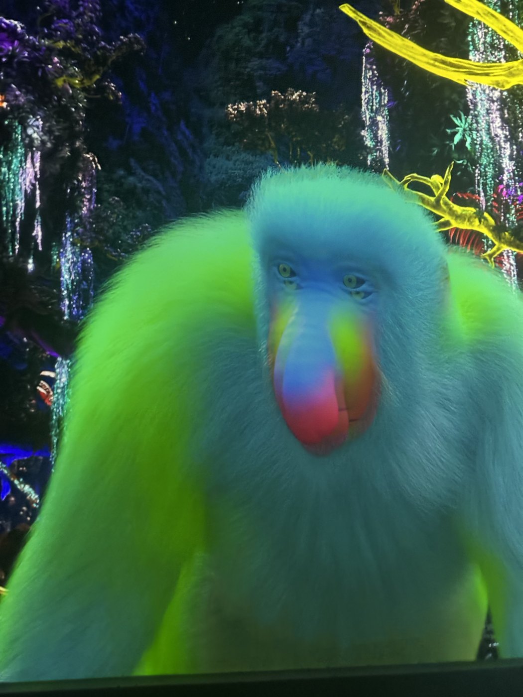 ジャングルの壁に映る、緑色に光るマンドリルの大きな映像