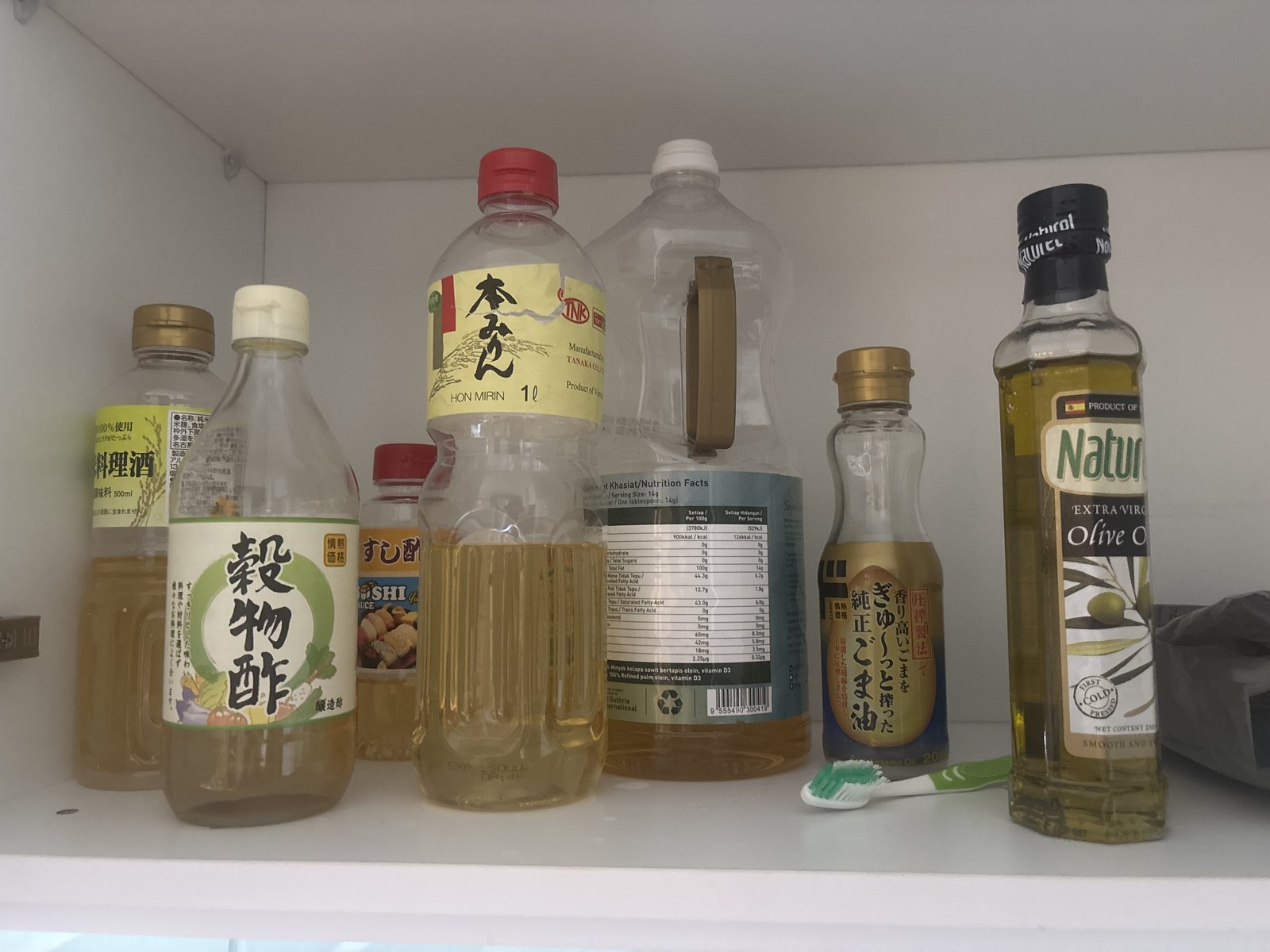 台所の棚。料理酒、情熱価格の穀物酢、すし酢、本みりん、純正ごま油