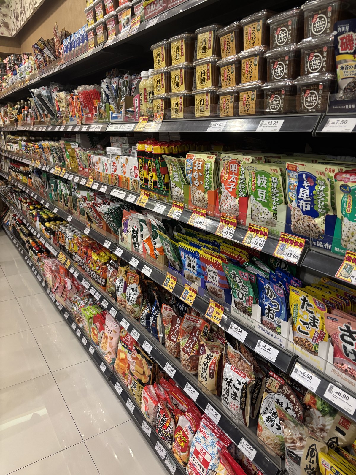 日本の食材の棚。ひかり味噌のカップ、丸美屋の混ぜ込みわかめ、ふりかけ、鍋の素
