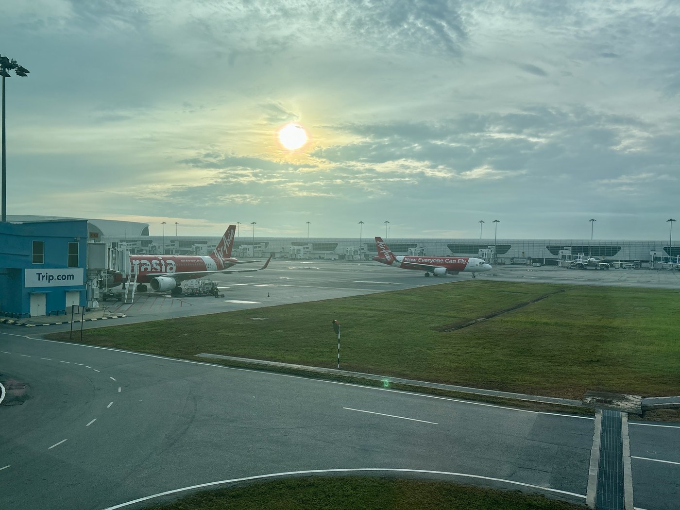空港の窓の外に並ぶ赤い尾翼の飛行機と朝日