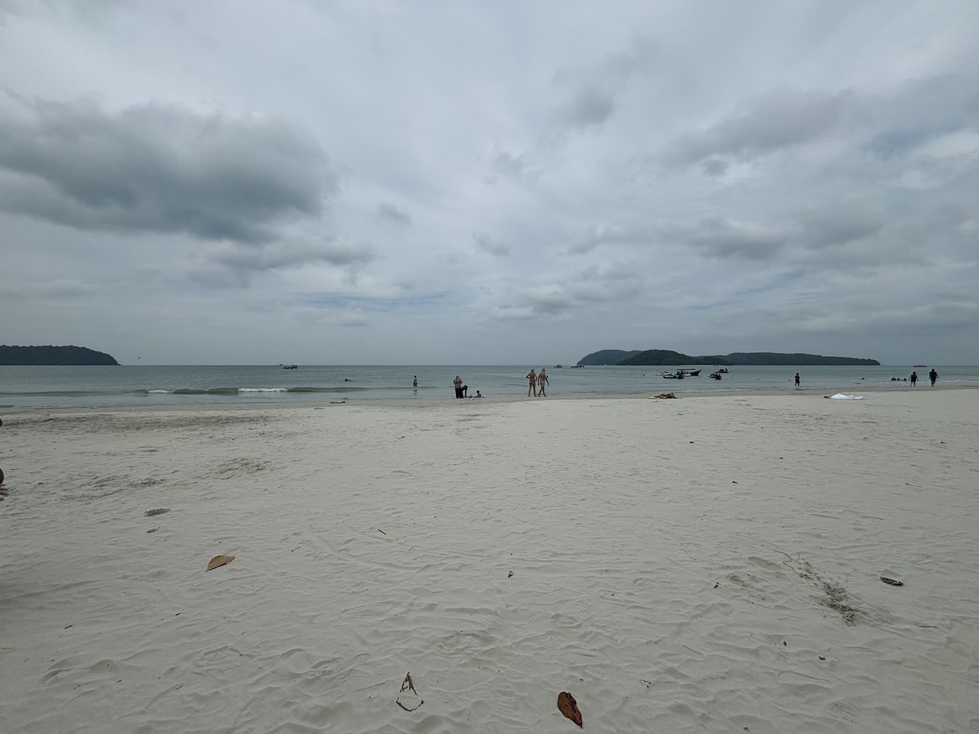 曇り空の下の白い砂浜と遠浅の海、沖の島