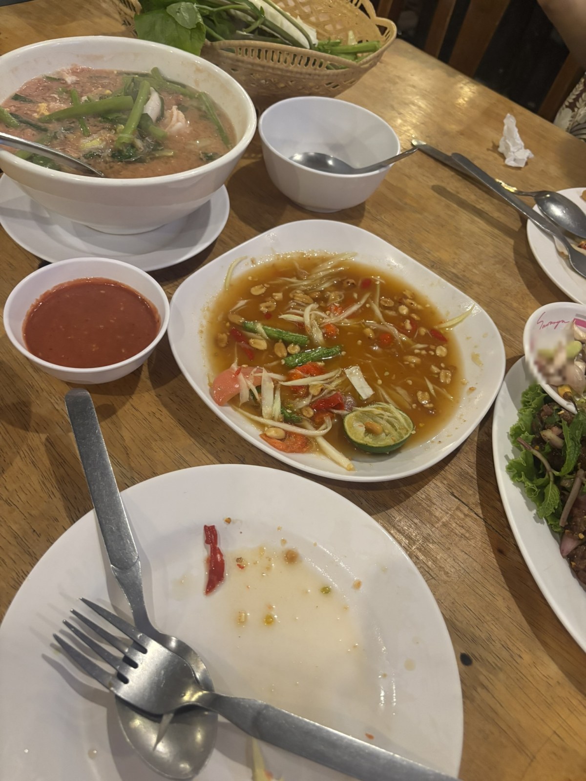ソムタムとスープと生野菜が並んだイサーン料理店のテーブル