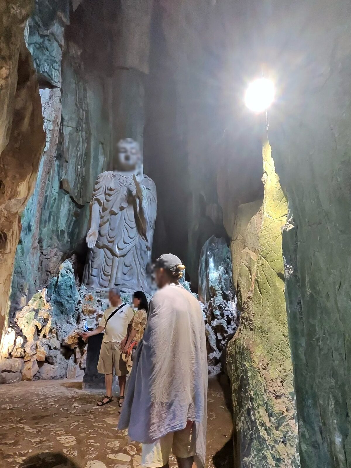 五行山の洞窟の中に立つ白い仏像と天井から差す光