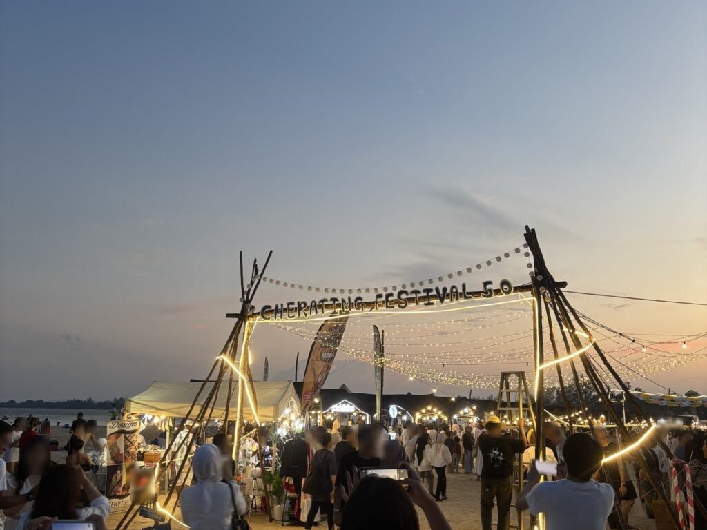 日没後、電飾のともった入口アーチと、屋台に集まる人